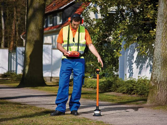 Technicien utilisant un capteur d’écoute au sol pour détecter le bruit d’une fuite sur une conduite